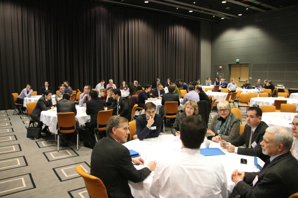 Photo of people sitting around tables in a big venue. 